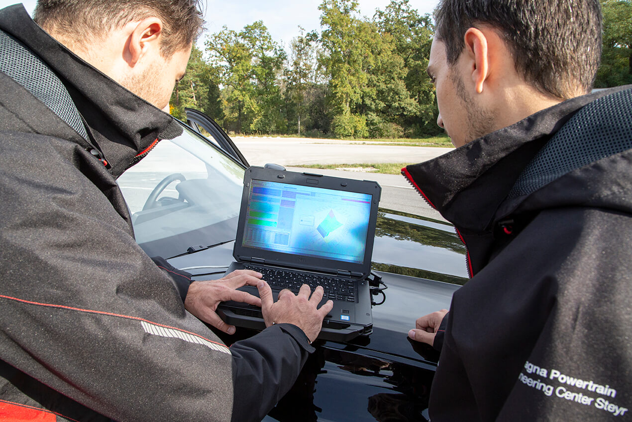 Propulsion System Calibration Two calibration engineers with notebook on the test track analysing vehicle measurement data using specific calibration tool.